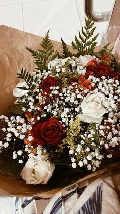 a bouquet of red and white flowers sitting on top of a piece of brown paper