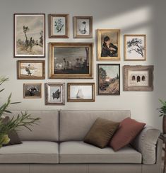 a living room filled with lots of framed pictures on the wall above a beige couch