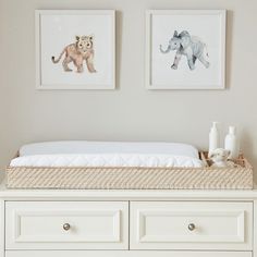 a baby's crib with two pictures on the wall above it and an elephant print