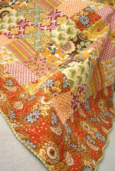 a multicolored patchwork table cloth is laying on the white floor and it looks like an old quilt