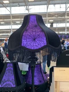 purple and black lampshade with fringes on display in a store or showroom