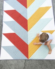 a baby is playing with a quilt on the ground