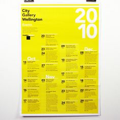 a yellow poster hanging on the wall in front of a white wall with black numbers