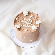 a chocolate cake with white flowers on top is sitting on a marble platter and has the words happy birthday edible written on it