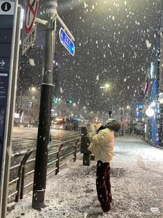 a person standing in the snow next to a street sign