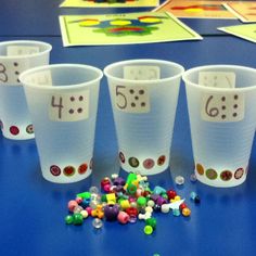 four plastic cups with numbers and candy on the table