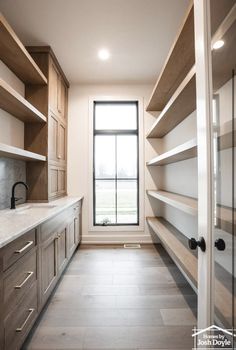 an empty walk in closet next to a window with lots of shelves on the wall