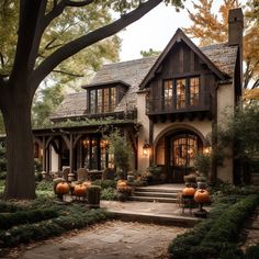 a house with pumpkins in front of it and trees around the entrance to the home