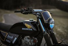 a black motorcycle parked on the side of a road next to a grass covered field