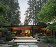 a modern house in the woods with steps leading up to it's front door