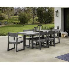 an outdoor dining table and chairs set on concrete patio with grass in the back ground