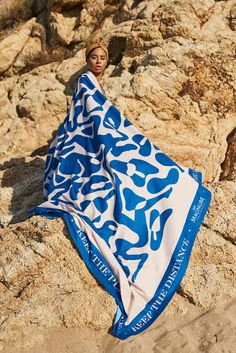 a woman wrapped in a blue and white towel on top of a rocky mountain side