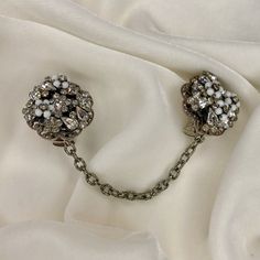 "A very nice pair of sweater clips from repurposed vintage unsigned clear rhinestone and milk glass bead costume earrings, found with one broken clip.   These repurposed flower cluster has clear rhinestones scattered on a silver tone filigree framework, accented with tiny wired milk glass bead flowers. Each earring is about 1.25\" across Settings and chains are gold or silver tone base metal, all from pre-owned vintage elements.   Chains are 3.5-4\"long. Clips are new; they are  cushioned and safe for most fabrics. if you have a pair of old screw back or clip on earrings, I can make them into sweater clips.  Write for information." Bead Flowers, Italian Gifts, Sweater Clips, Collar Clips, Vintage Elements, Sweater Clip, Flower Cluster, Costume Earrings, Repurposed Vintage