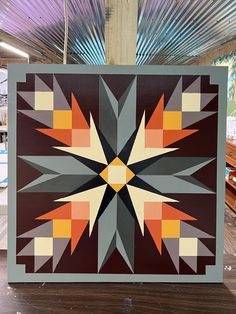 an abstract quilt is displayed on a wooden table