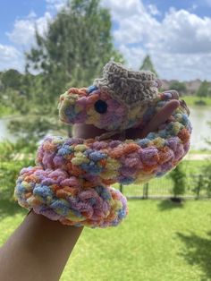 a hand is holding up a crocheted teddy bear in a knitted scarf