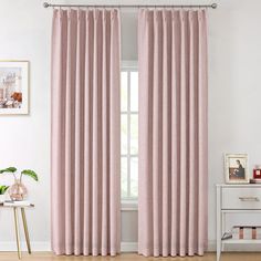 a pink curtain hanging in front of a window with white walls and wooden flooring