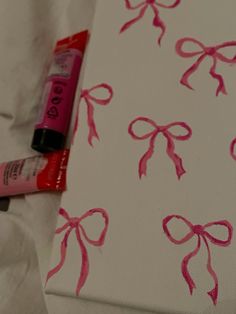 a painting with pink bows on it next to a tube of lip balm lipstick