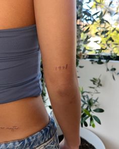 the back of a woman's left arm with a small tattoo on her right side