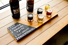 a wooden table topped with three different types of beers and a sign that says nu brown