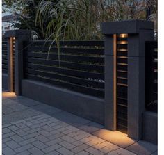 a black fence with lights on it and some plants in the back ground next to it