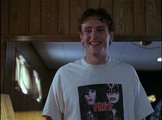 a young man is smiling while wearing a kiss t - shirt