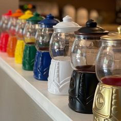 there are many different colored glass jars on the shelf