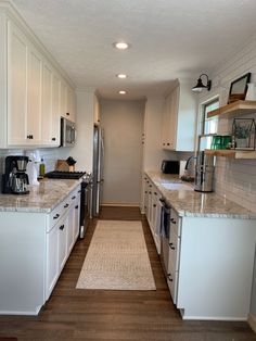 a long narrow kitchen with white cabinets and wood flooring is seen in this image