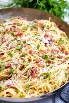 pasta with bacon and parmesan cheese in a pan on top of a table