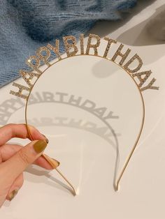 a woman is holding up a happy birthday headband with glitter letters on the side