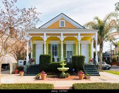 a yellow and white house with a fountain in the front yard