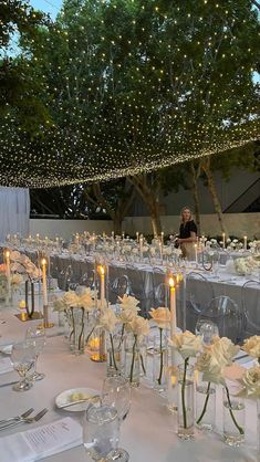 the tables are set up with clear vases filled with white flowers and lit candles