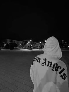 black and white photograph of person in hoodie looking at the street with lights on