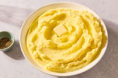 a bowl filled with mashed potatoes next to a small bowl full of butter and seasoning