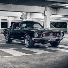 an old black mustang sitting in a parking lot