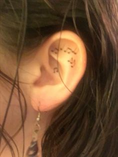 a woman's ear with the word love written on it and two small stars behind her ear