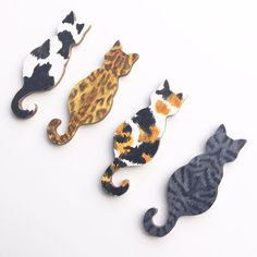 three different types of cat magnets on a white surface, one is orange and the other is black