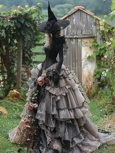 a woman in a black dress and hat with flowers on her head is standing outside