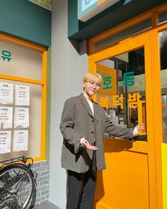 a woman standing in front of a yellow and green building with her hands out to the side