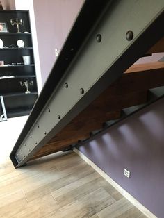 the bottom half of a metal stair case in a room with purple walls and wooden flooring