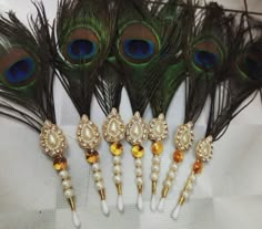 peacock feathers and pearls are arranged on a white tablecloth with gold - colored beads