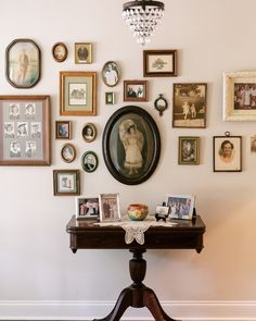 the wall is covered with many different pictures and framed photos, including an old fashioned table