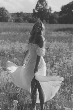 a woman in a dress is walking through a field