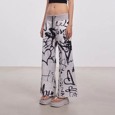 Embrace the perfect fusion of playful charm and street style with our Doodle Full-Print Wide-Leg Pants. These pants are adorned with vibrant cartoon doodles printed all over, creating a unique and eye-catching look. The waistband features a knitted ribbed design with an adjustable drawstring for a comfortable and customizable fit. Designed with a low-rise waist, these pants offer a relaxed, oversized fit, ensuring both comfort and style. Crafted from premium fabric, they are durable and perfect Casual Baggy Printed Bottoms, Playful Wide-leg Summer Pants, Wide Leg Pants With Graphic Print For Spring, Summer Cotton Bottoms With Graffiti Print, Casual Printed Straight Leg Bottoms, Casual Full-length Printed Pants, Casual Full Length Printed Pants, Trendy Cotton Bottoms With Graffiti Print, Casual Graffiti Print Bottoms For Streetwear