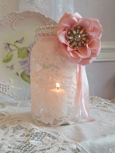 a pink vase with a flower on top of it and candles in front of it