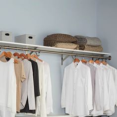 an organized closet with clothes hanging on rails