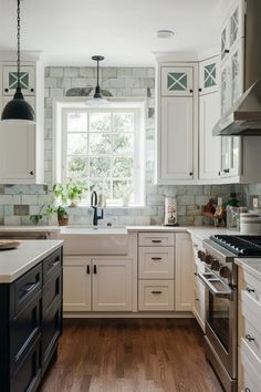 a kitchen with white cabinets and wood floors is pictured in this image, there are two windows above the sink