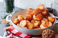 a bowl filled with fried potatoes on top of a wooden cutting board