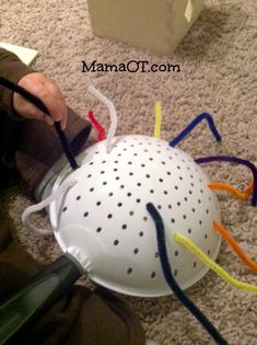 a child is playing with a white ball on the floor and wires coming out of it