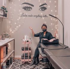 a woman wearing a face mask sitting in front of a wall with lashes on it