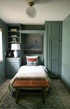 a bedroom with green painted walls and a white bed in the middle, surrounded by built - in bookshelves